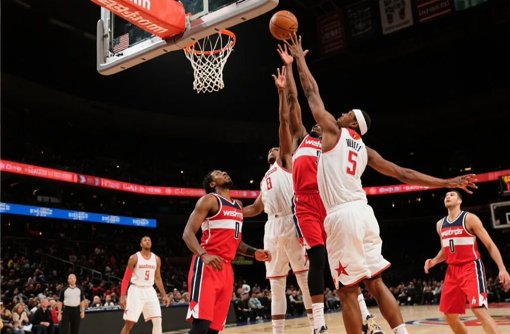 篮球比赛中两队球员激烈争抢篮板球，场面紧张，动作迅速，现场氛围高涨